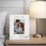 Drveni bijeli okvir za fotografije s rukom ispisanim imenima i ljubavnom porukom za mladence.