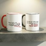 Set od dvije keramičke šalice jedna s crvenom ručkom i natpisom Dao bih ti punjač na 1% a druga s crnom ručkom i natpisom Volim te više nego što volim spavati.